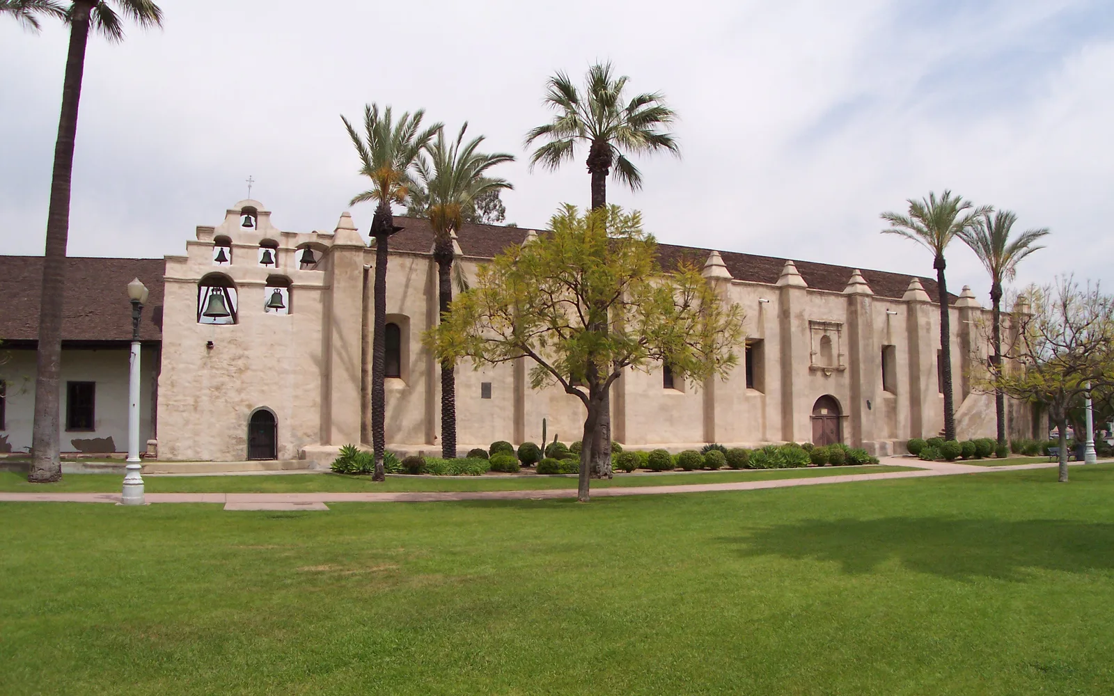 Front view of Mission San Gabriel Arcángel church with white walls and bell tower